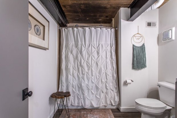 Main-floor bathroom with a pintuck shower curtain beneath a timber plank ceiling