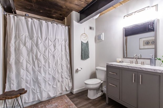 Main-floor bathroom with a grey vanity, marble top and framed mirror