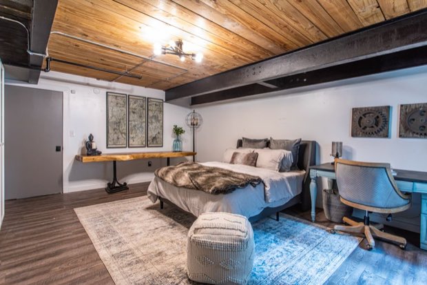 Main-floor bedroom with a live-edge console, desk and timber plank ceiling