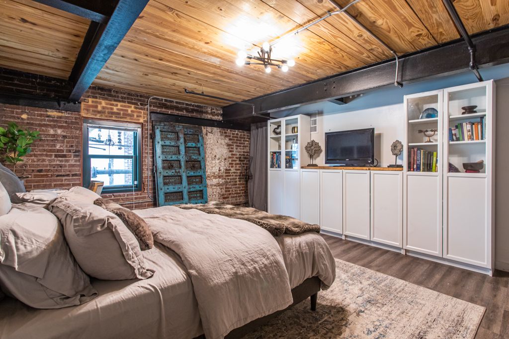 Main-floor bedroom with an exposed brick wall, antique turquoise doors and a factory window