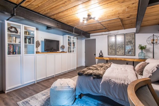 Main-floor bedroom with white built-in cabinetry beneath a timber and steel ceiling