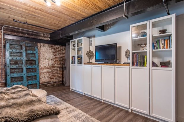 Built-in storage wall beside the antique turquoise doors and exposed brick