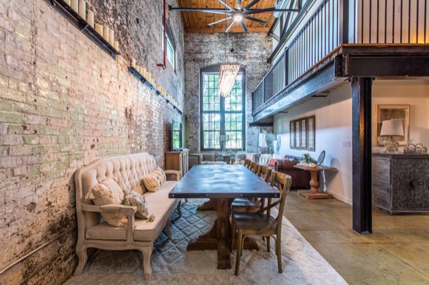 Dining table for eight along the brick wall, beneath the mezzanine