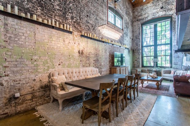 Dining table beneath a crystal chandelier, with candles ranged along a steel rail