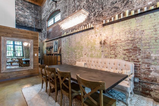 Dining table against the brick wall with the kitchen beyond