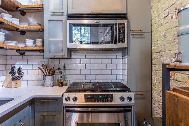 Galley kitchen with subway tile, a gas range and open pipe shelving