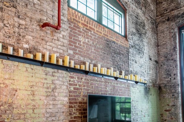 Candles ranged along a steel rail on the double-height brick wall