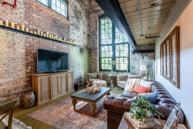Living room with the television on exposed brick and the factory window beyond