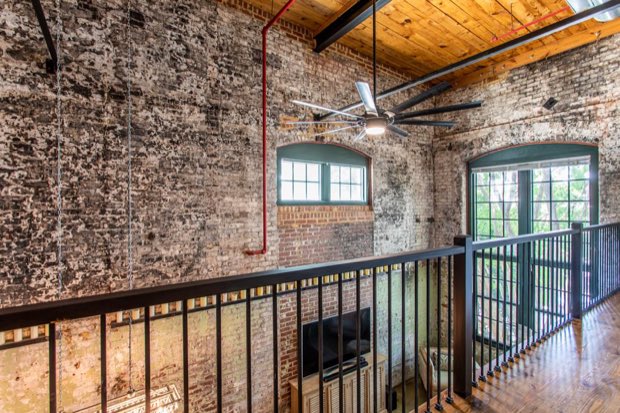 Mezzanine with a ceiling fan, arched windows and exposed brick