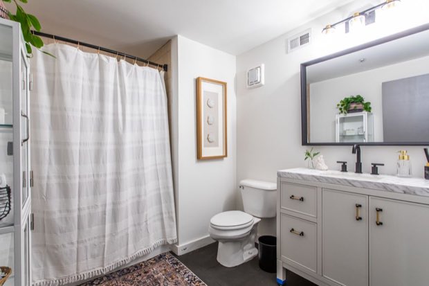 Loft bathroom with a grey vanity, marble top and black framed mirror
