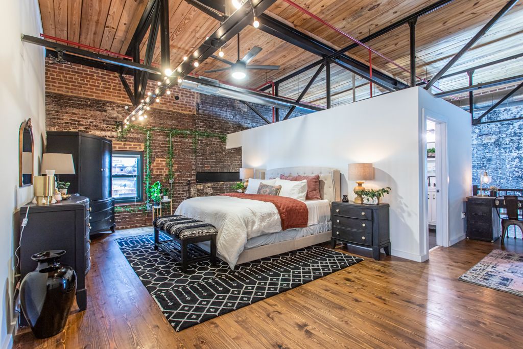 Loft bedroom beneath the timber ceiling and steel trusses, strung with cafe lights