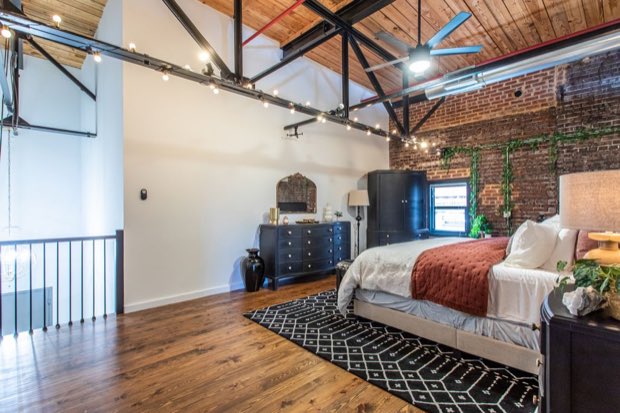 Loft bedroom with black dressers and an armoire against the white partition