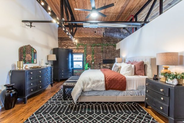 Loft bedroom with an upholstered bed, brick wall and trailing ivy