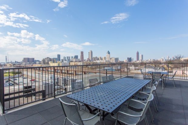 Rooftop deck with dining tables and the Atlanta skyline beyond