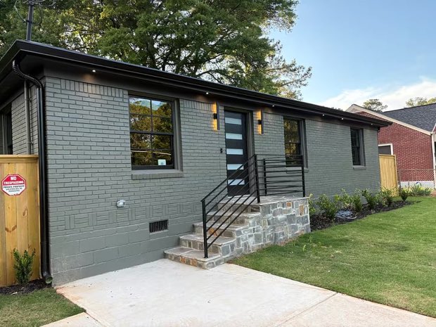 Front exterior of the Glenwood Hills mid-century modern home in Decatur, charcoal painted brick with a black steel handrail