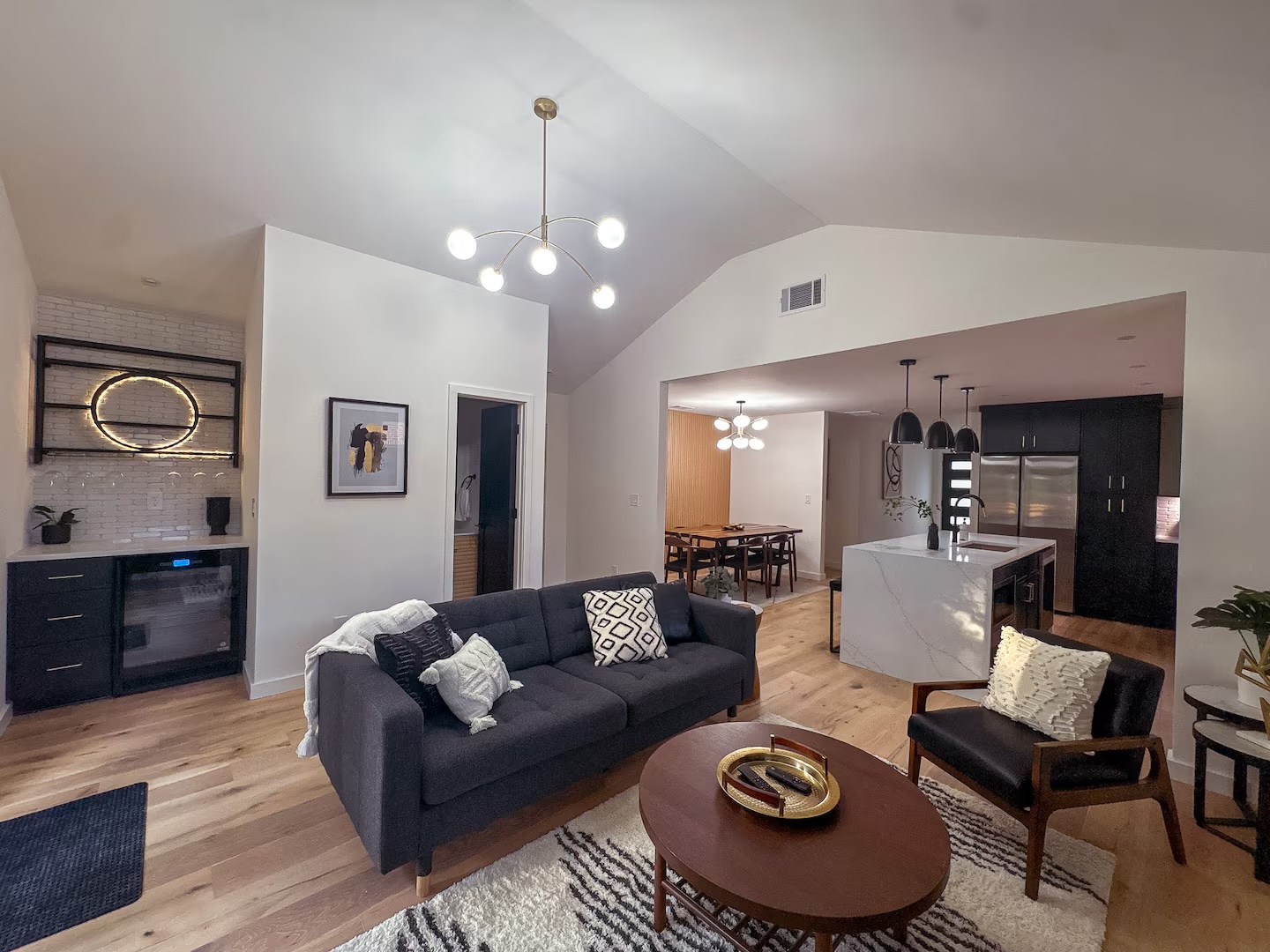 Open living, dining and kitchen with white oak floors and a marble waterfall island