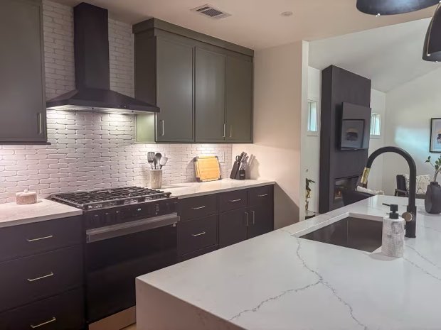 Kitchen range wall with a gas range, vent hood and white brick tile backsplash