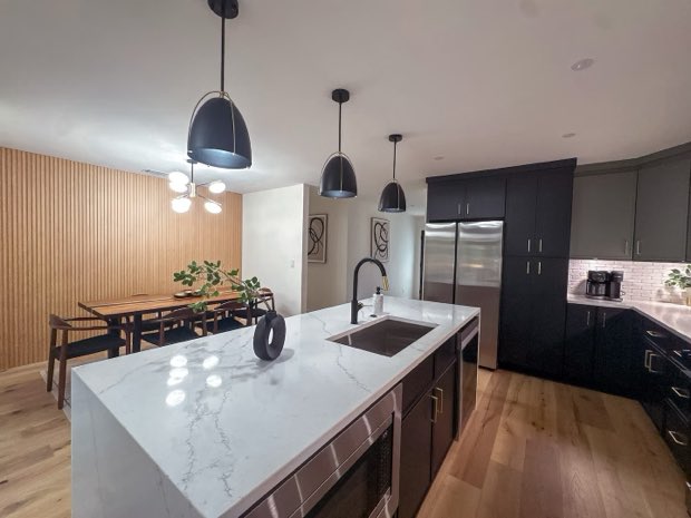 Quartz island with an undermount sink and pendant lighting, looking through to the dining area
