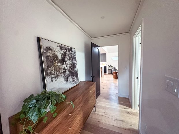 Hallway with a walnut dresser and abstract art, looking through to the kitchen