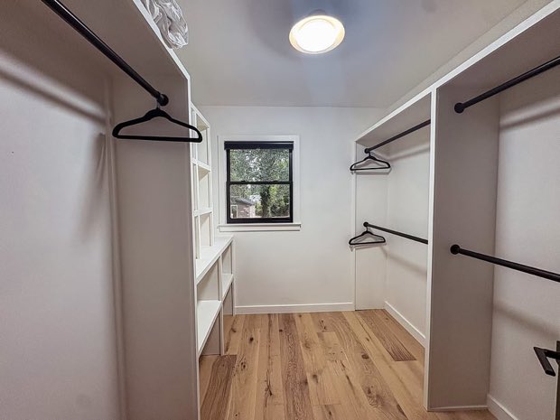 Primary walk-in closet with double hanging rods and built-in shelving