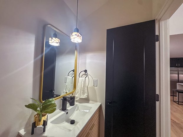 Guest bathroom with a brass-framed mirror, pendant light and wood vanity