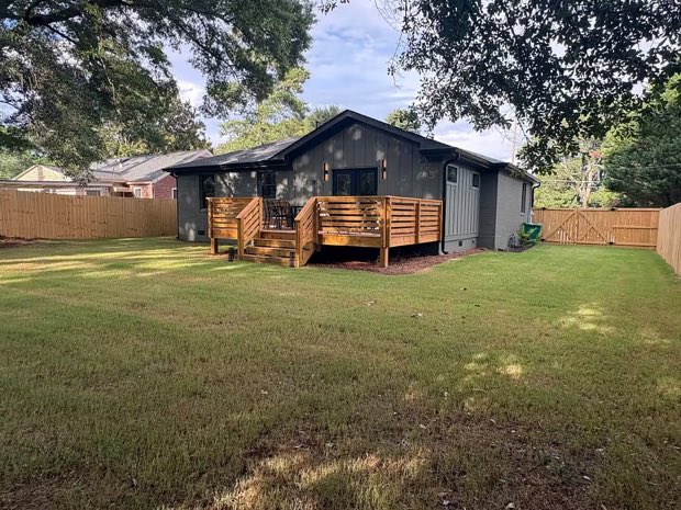 Rear exterior of the home with its flat, fenced backyard