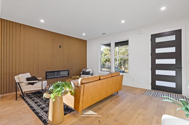 Living room with a wood slat fireplace wall, looking toward the front door