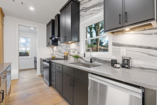 Kitchen run with dark cabinetry, a dramatic marble slab backsplash and stainless appliances