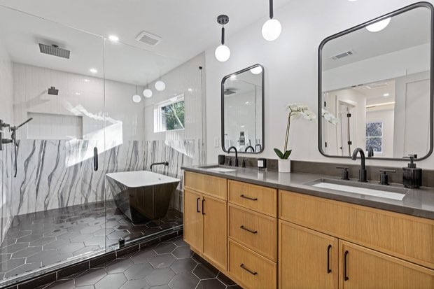Primary bathroom double vanity with wood cabinetry