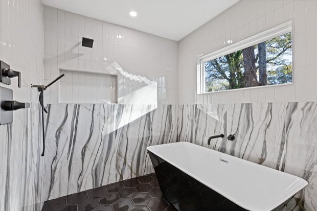 Freestanding tub and walk-in shower with marble slab walls and hexagon tile floor