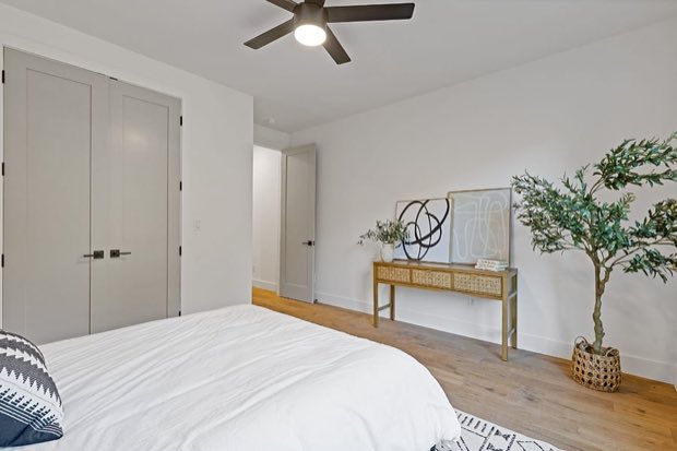 Bedroom with a cane console table, framed art and double closet doors